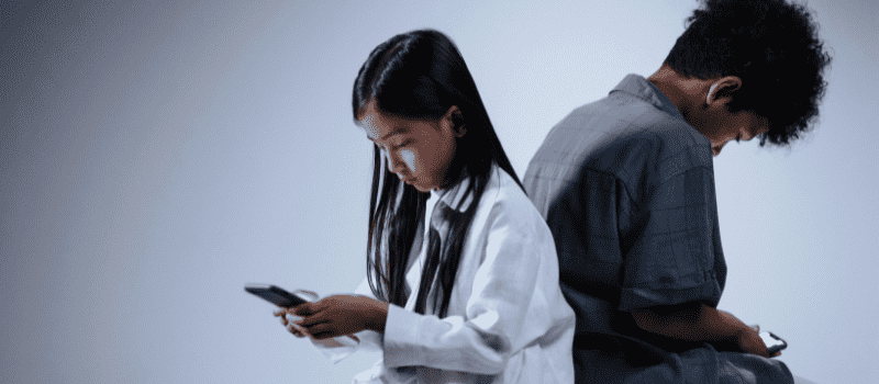 Two children looking down at their phones, reflecting emotional isolation and the silent struggles many people experience, highlighting the importance of connection in a healing journey.